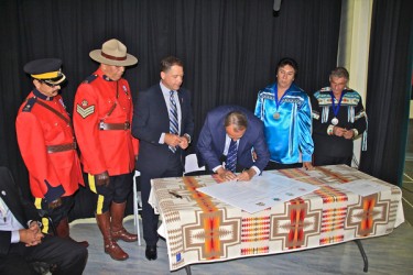 Federal minister John Duncan signs the settlement agreement while provincial min
