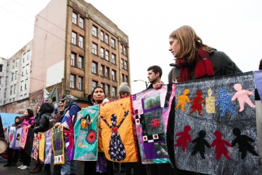 Several long strings of colourful quilted, embroidered or beaded squares each ho